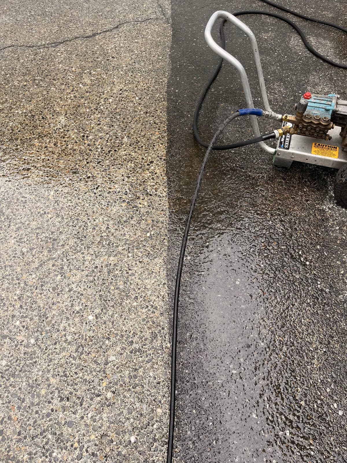 Driveway mid pressure-wash showing the sharp line between cleaned and untouched pavement